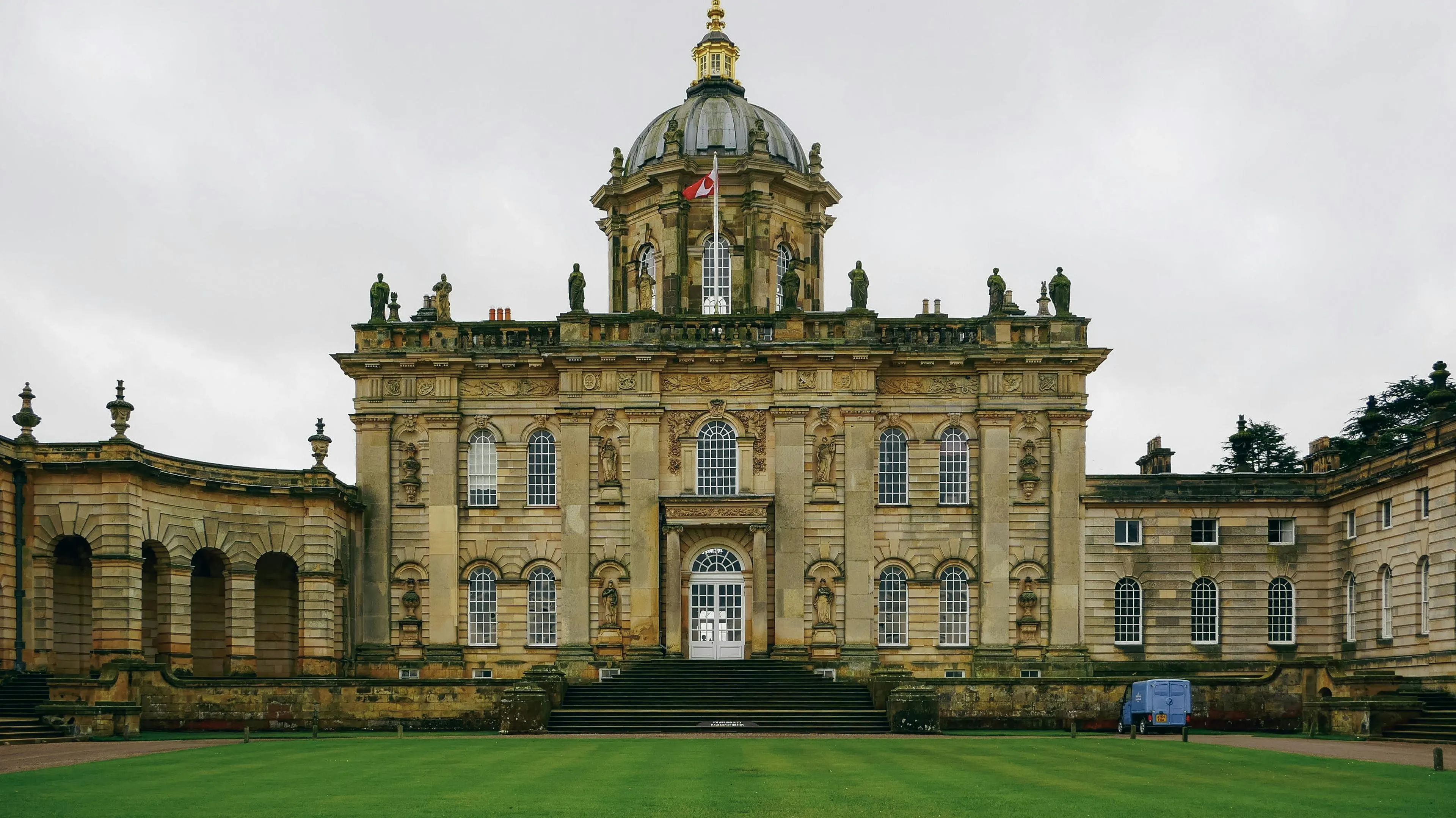 Castle Howard dome glowing at sunrise with formal gardens, lake reflection, and Yorkshire woodland background in North Yorkshire