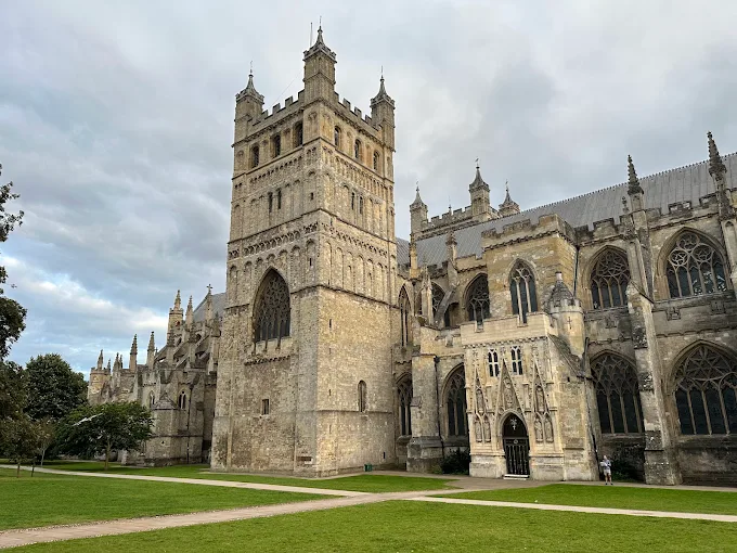 Exeter Cathedral Gothic spires rising above historic close at golden hour with stone walls in Devon England