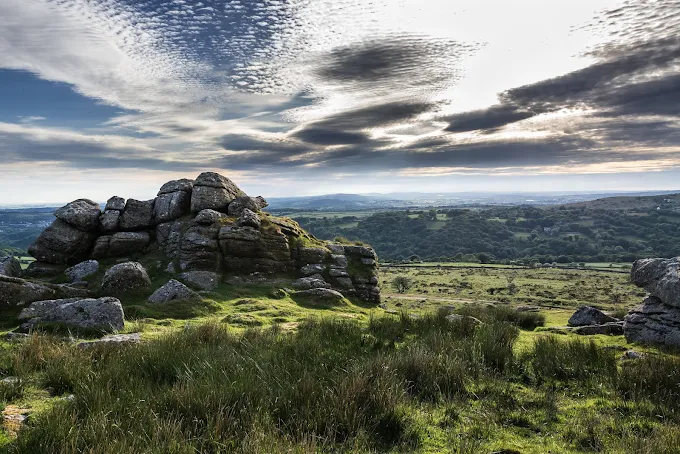Dartmoor National Park granite tors shrouded in morning mist with wild ponies grazing on heathland in Devon England