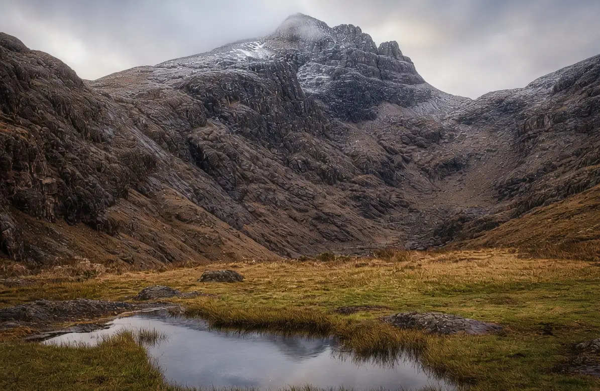 Ben Nevis mountain summit at sunrise with rocky granite peak, misty clouds, and Scottish Highlands background in Fort William