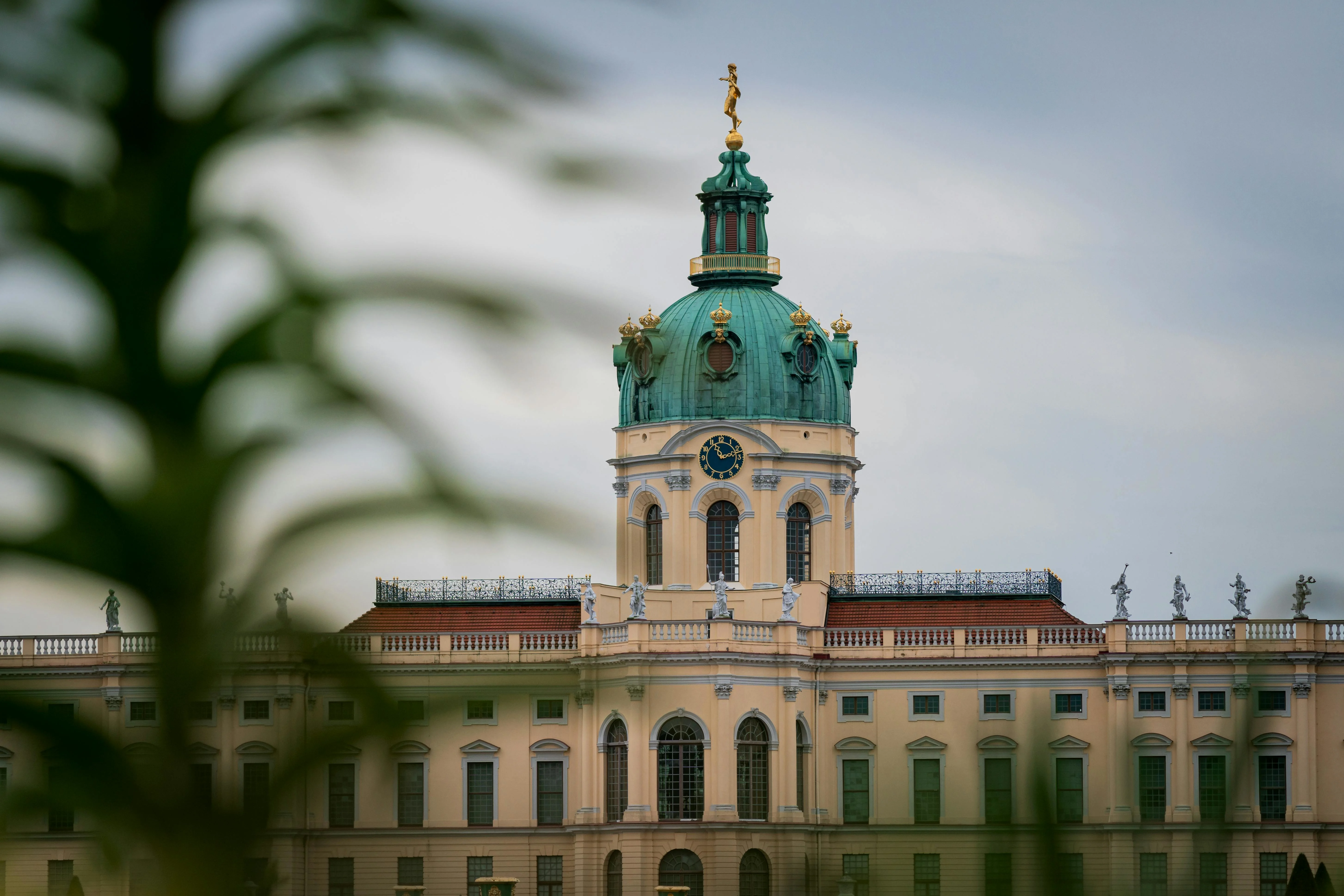 Golden dome of Charlottenburg Palace at sunset with baroque facade, formal gardens, and Berlin skyline in Germany
