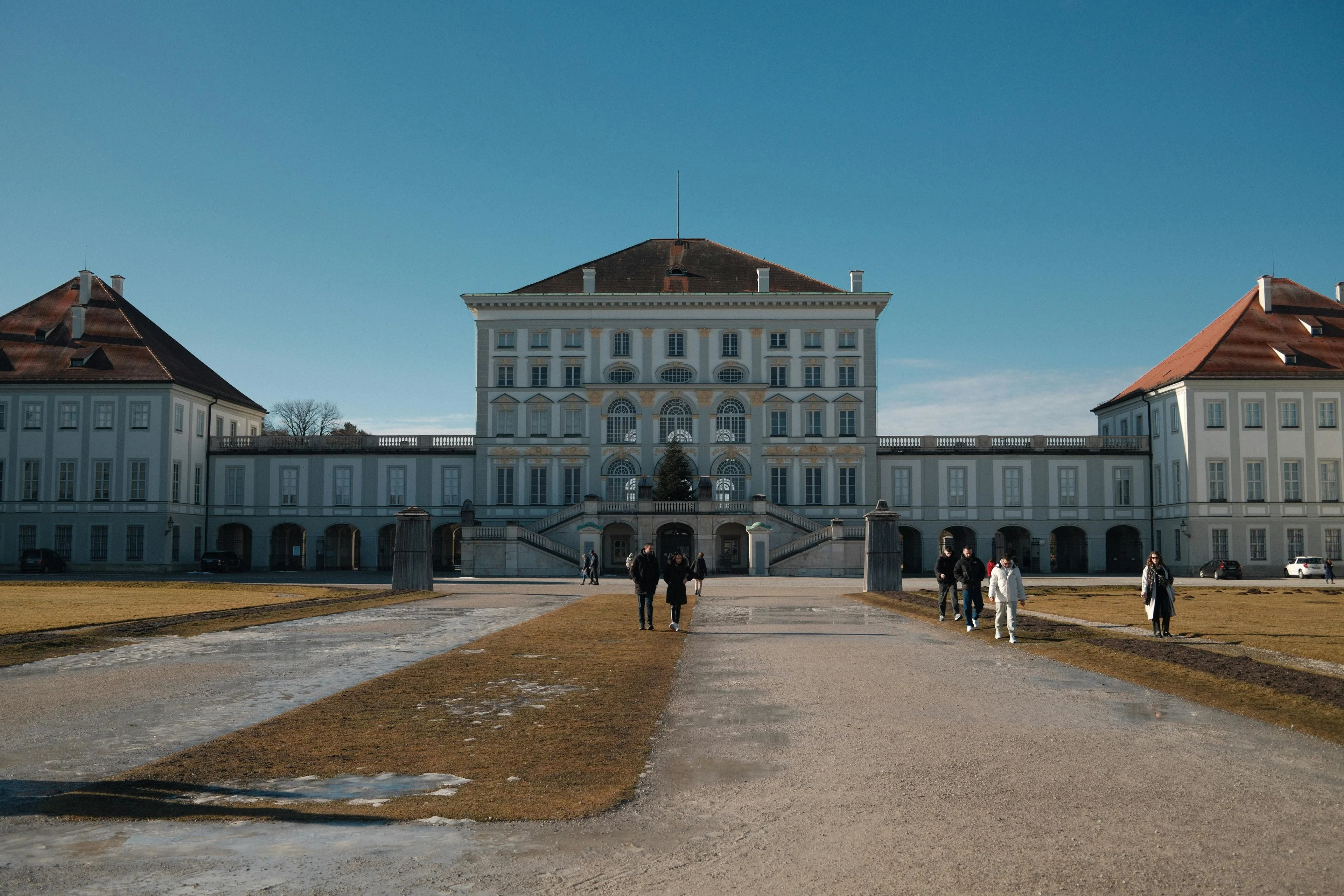 Nymphenburg Palace baroque facade at sunset with canal reflection, formal gardens, and Munich skyline in Bavaria Germany