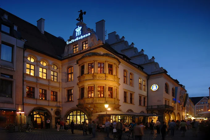 Hofbräuhaus beer hall interior at evening with wooden tables, hanging lights, and musicians playing in Munich Bavaria