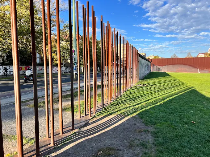 Berlin Wall Memorial preserved concrete segment at dawn with gray sky, watchtower silhouette, and Bernauer Straße background in Germany