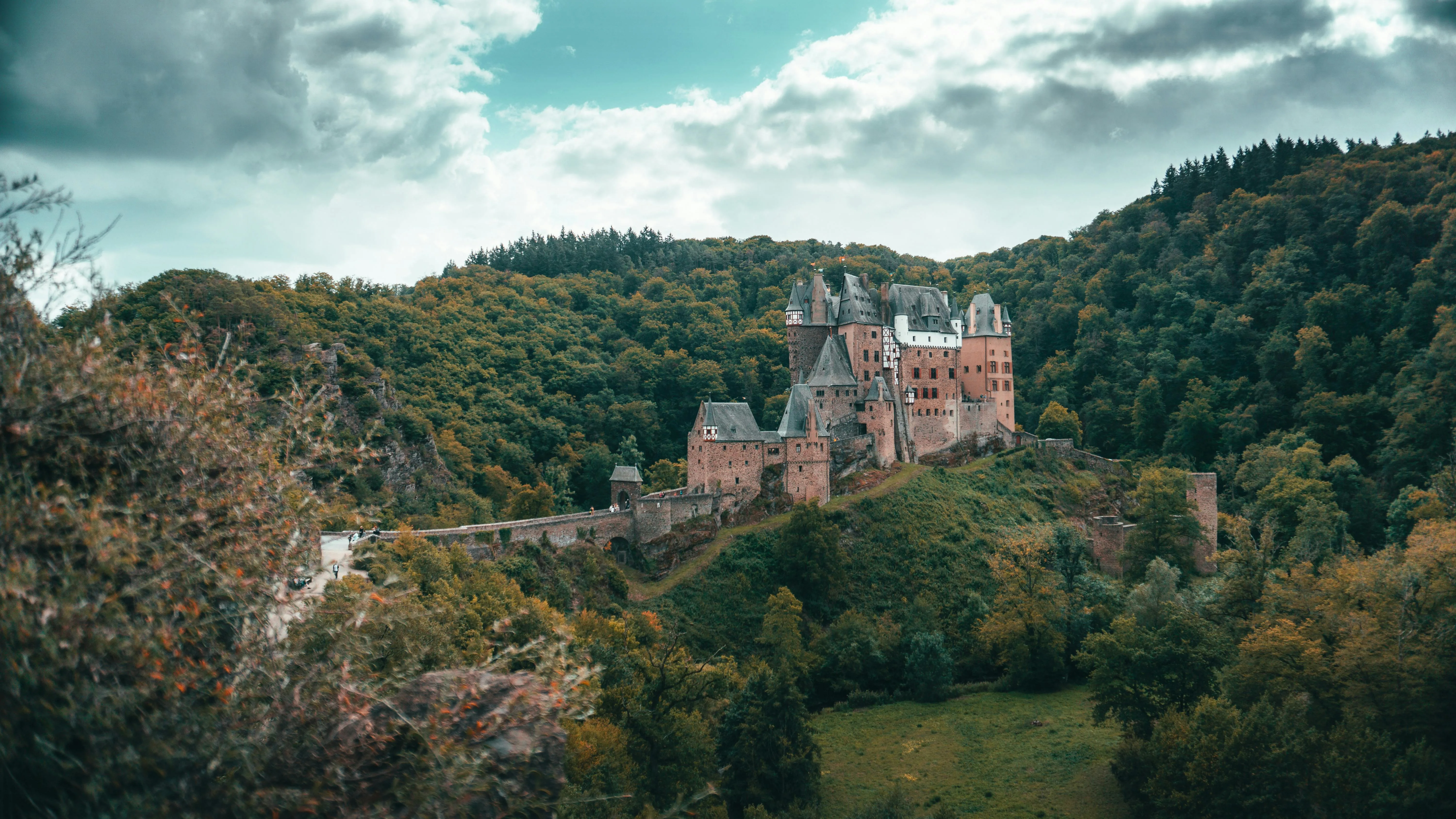 Burg Eltz medieval castle towers at sunrise with forest mist, slate roofs, and Rhine Valley background in Germany