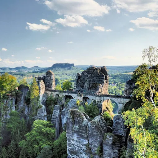 Bastei Bridge sandstone arch at sunrise with Elbe River valley, misty forest, and rock formations in Saxon Switzerland Germany