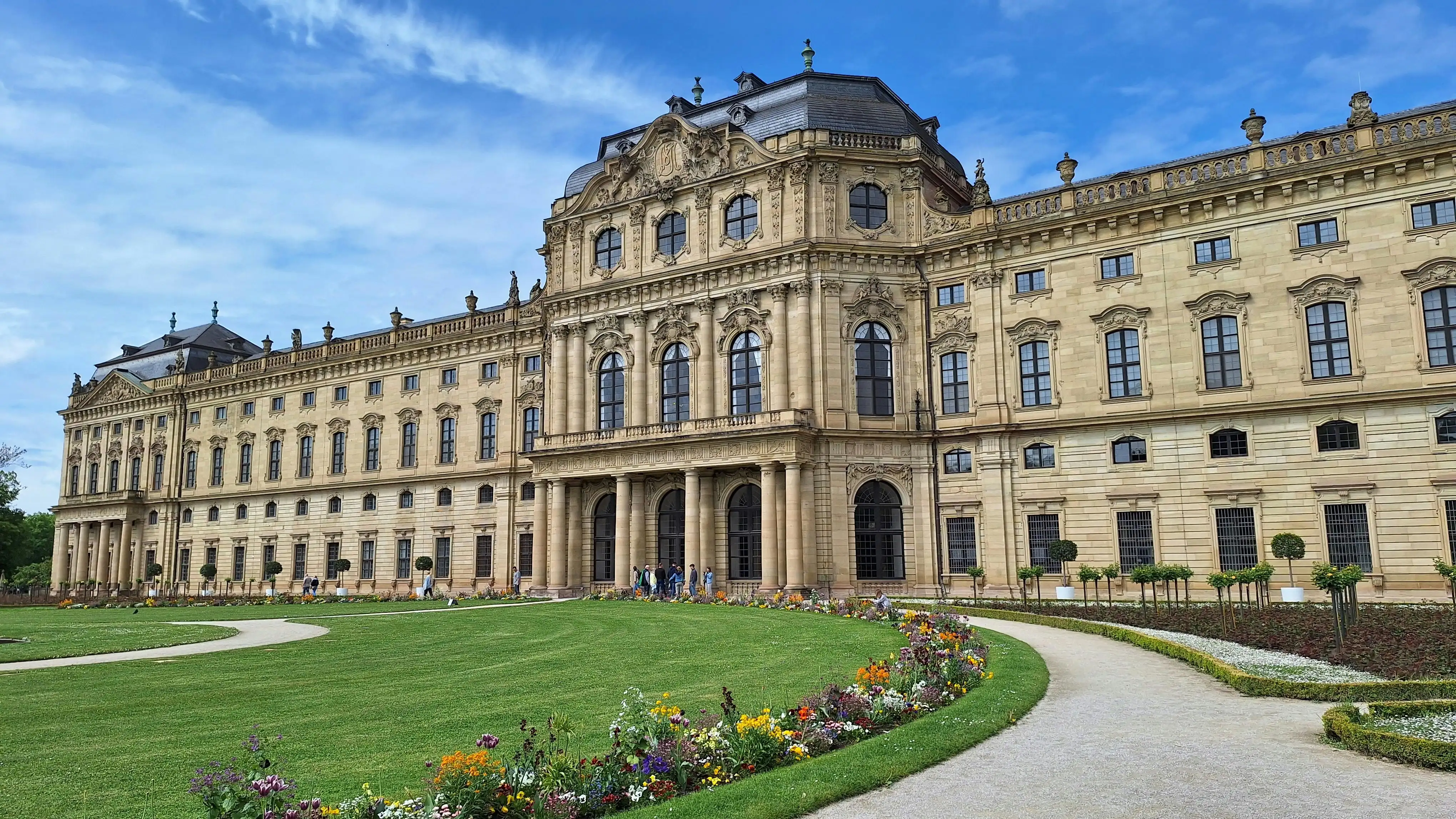 Würzburg Residenz palace facade at sunrise with Main River reflection, baroque architecture, and Franconian vineyards in Germany