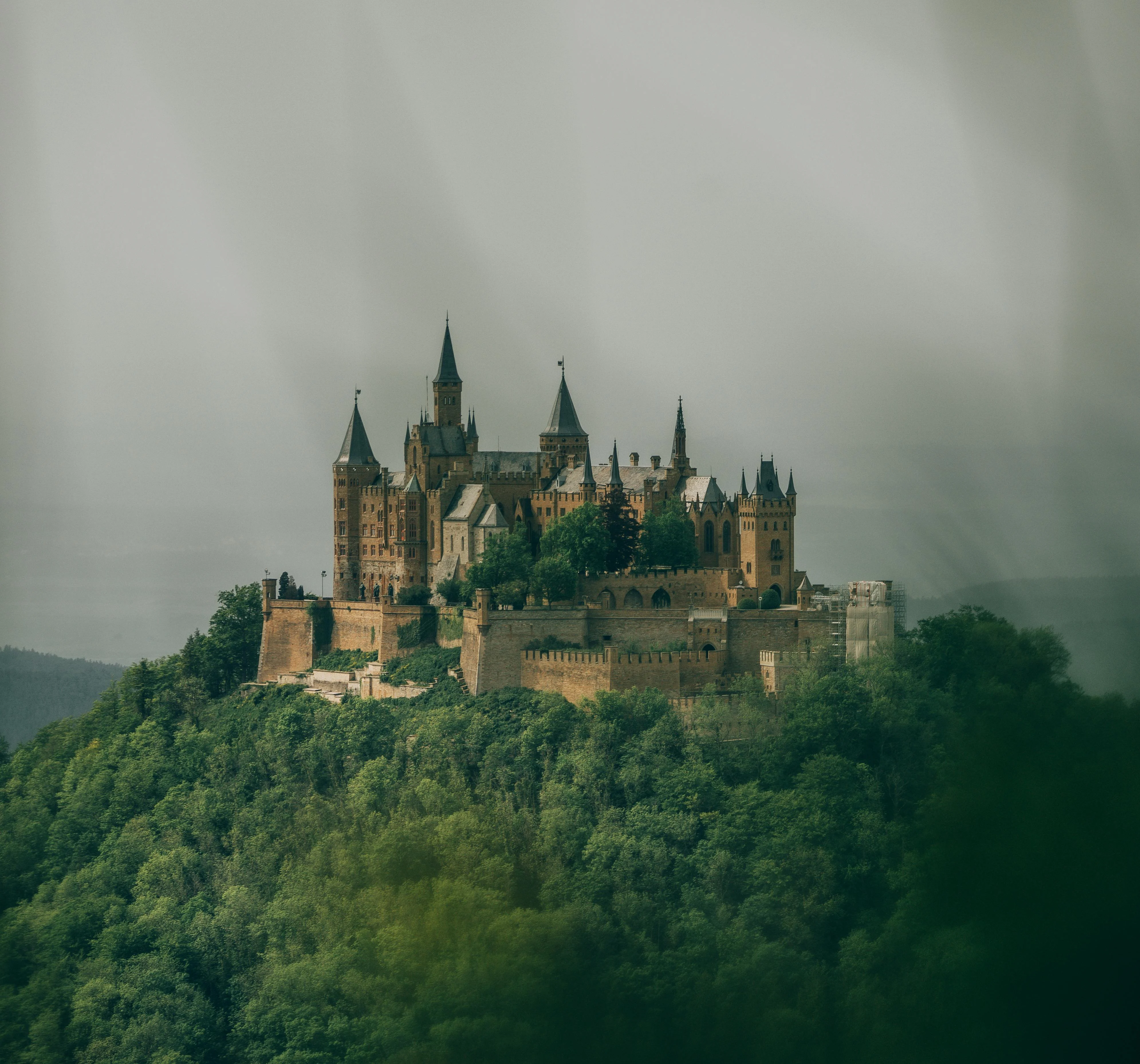 Hohenzollern Castle perched on mountain peak at sunrise with misty Swabian Alps and red stone towers in Germany