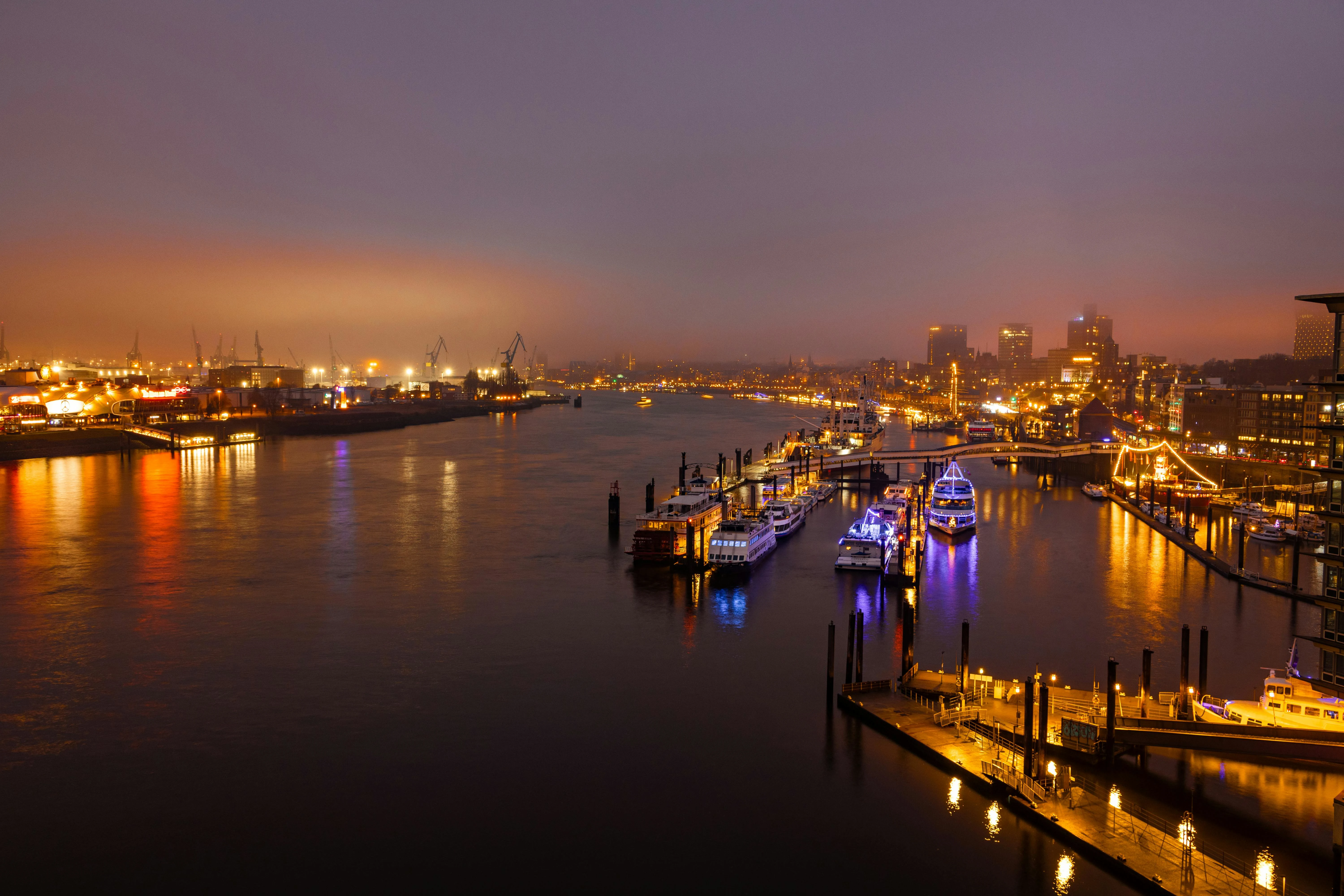 Hamburg Harbor container ships at sunrise with Elbe River reflection, cranes, and morning mist in Germany