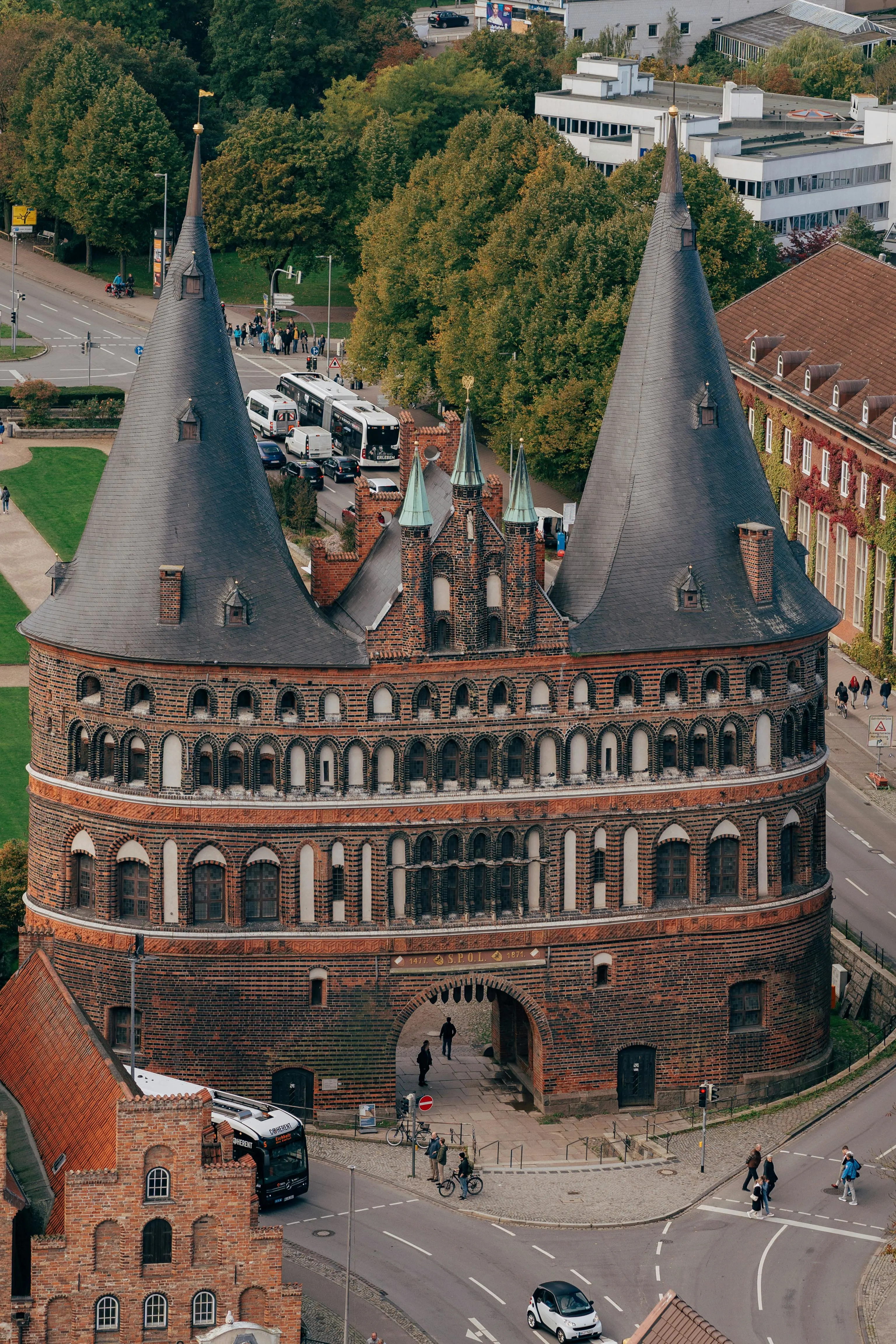 Lübeck Holstentor brick gate at sunrise with Trave River reflection, twin towers, and historic city skyline in Germany