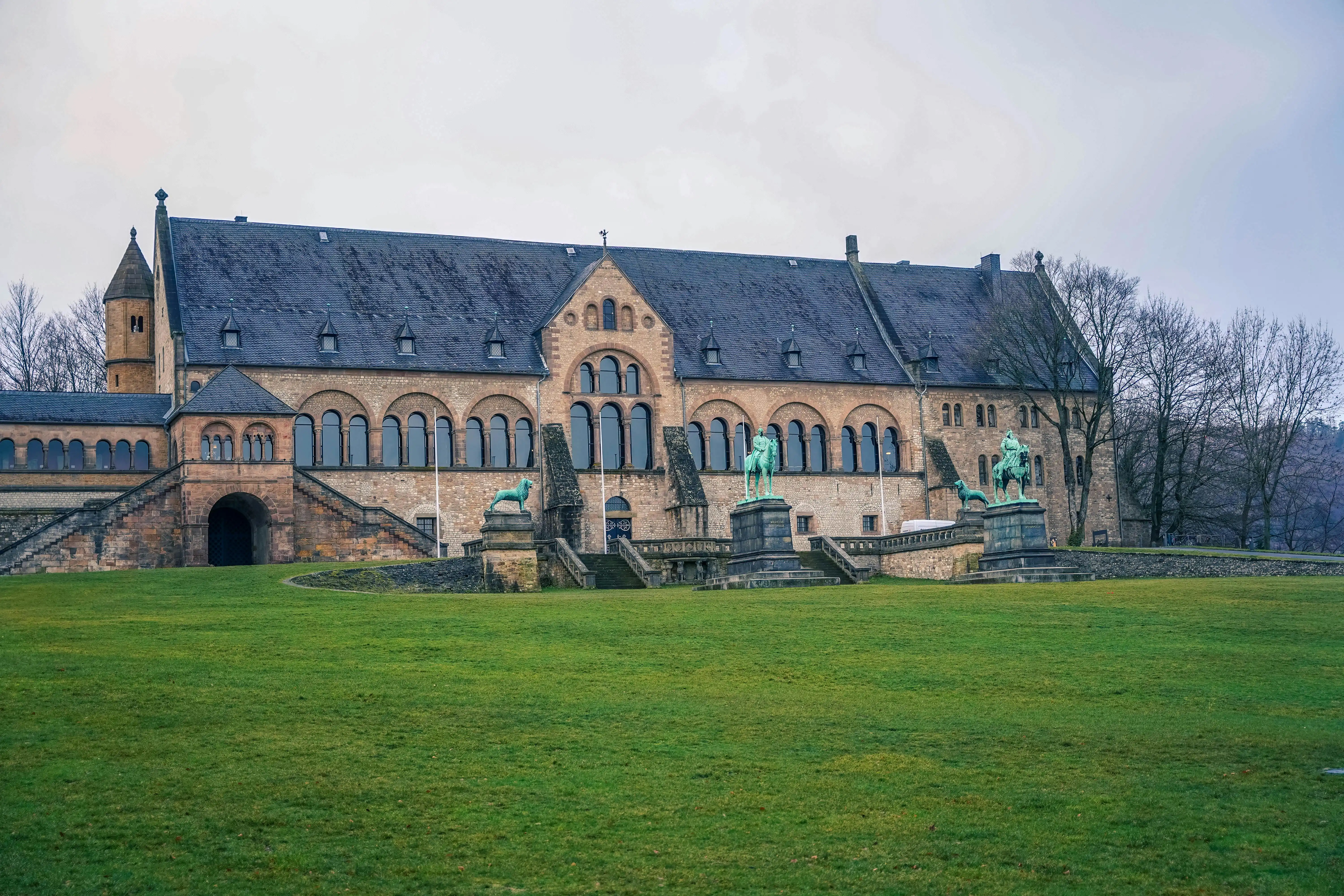 Goslar Imperial Palace Great Hall at sunrise with medieval stone facade, Harz Mountains backdrop, and morning mist in Germany