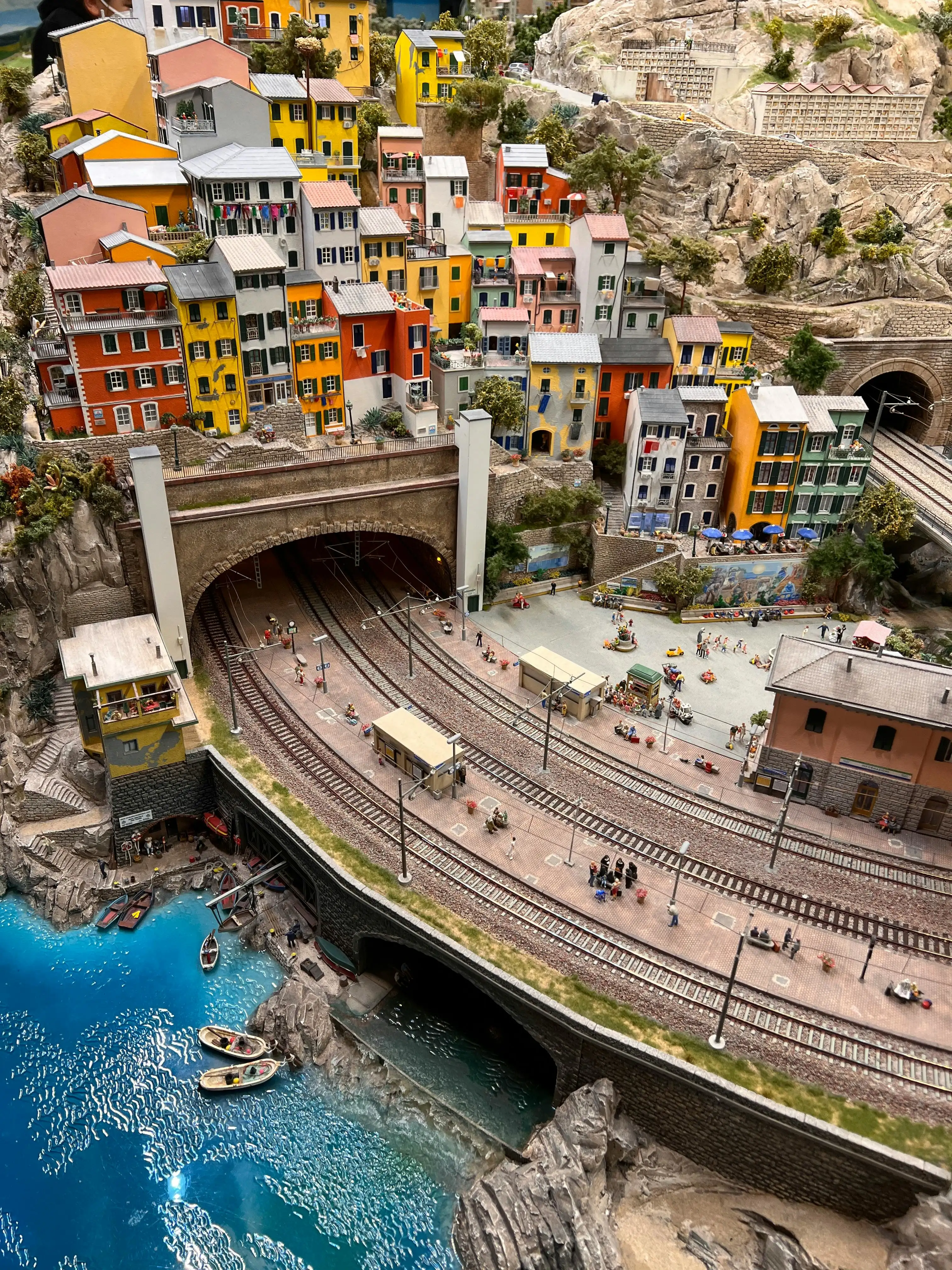 Miniatur Wunderland model railway layout at dusk with tiny trains, illuminated buildings, and detailed landscape in Hamburg Germany