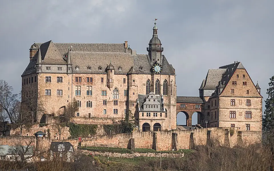 Marburg castle university at sunrise with red sandstone walls, Lahn River valley, and historic town in Germany