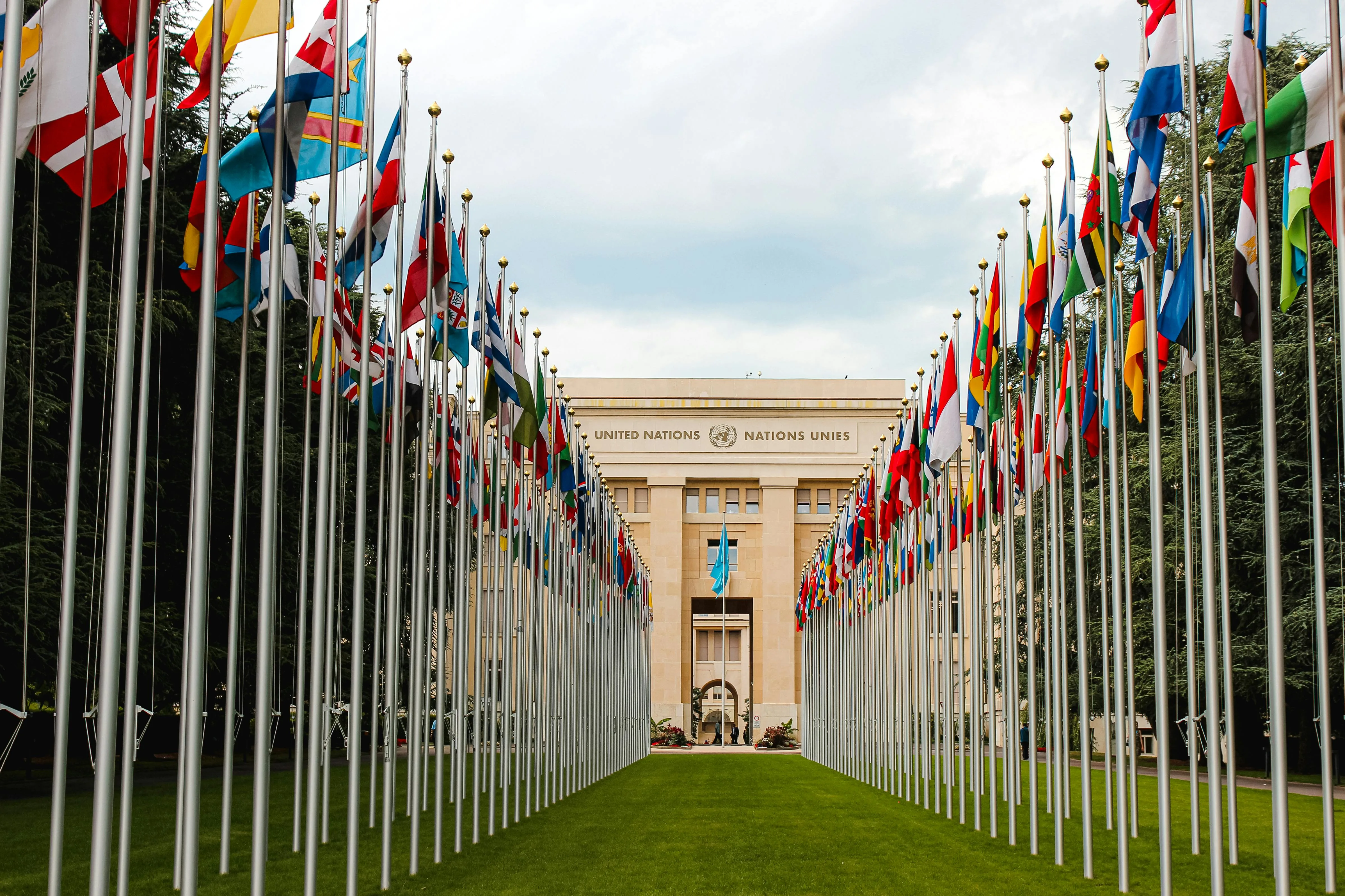 United Nations Palace Geneva at sunrise with Assembly Hall, Ariana Park greenery, and Lake Geneva view in Switzerland