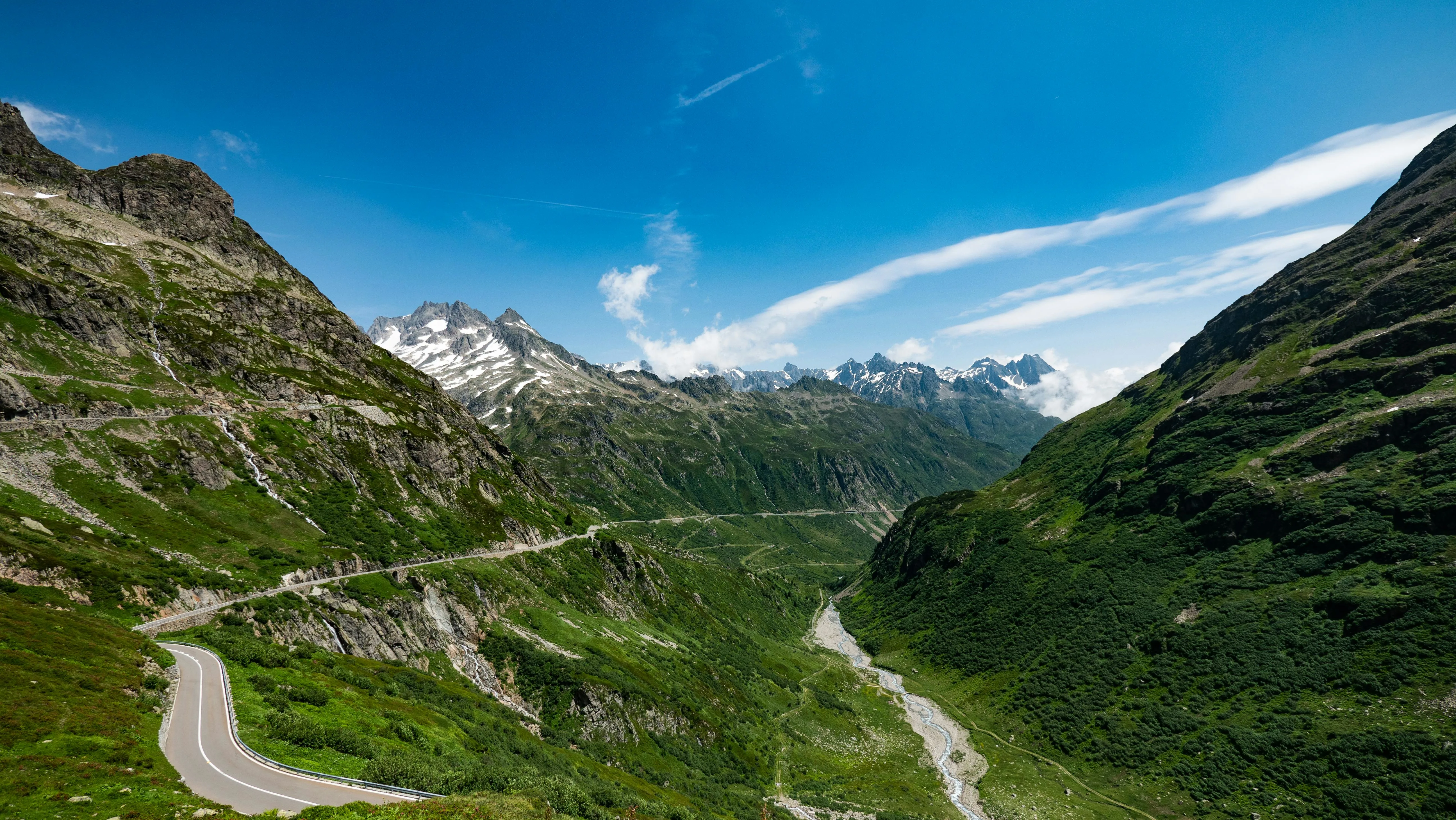 Susten Pass winding road at sunrise with alpine peaks, glacial valley, and morning mist in Switzerland