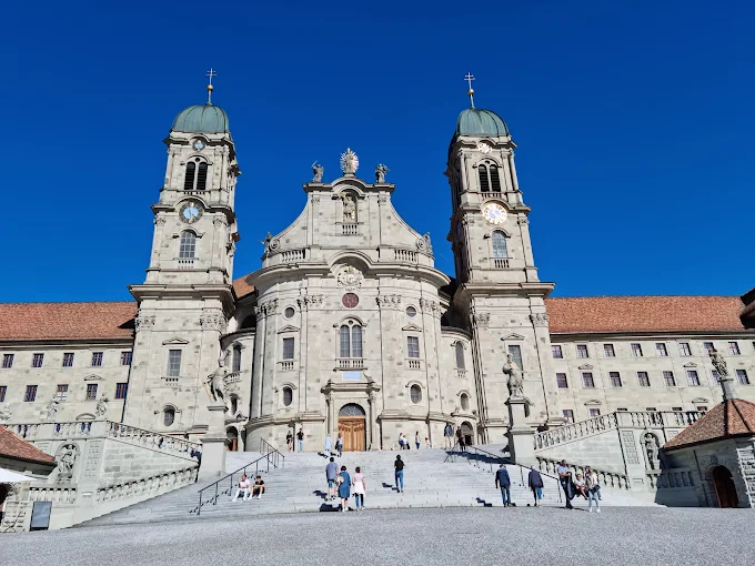 Einsiedeln Monastery baroque facade at sunrise with twin towers, pilgrimage square, Schwyz canton morning light and Alpine mist