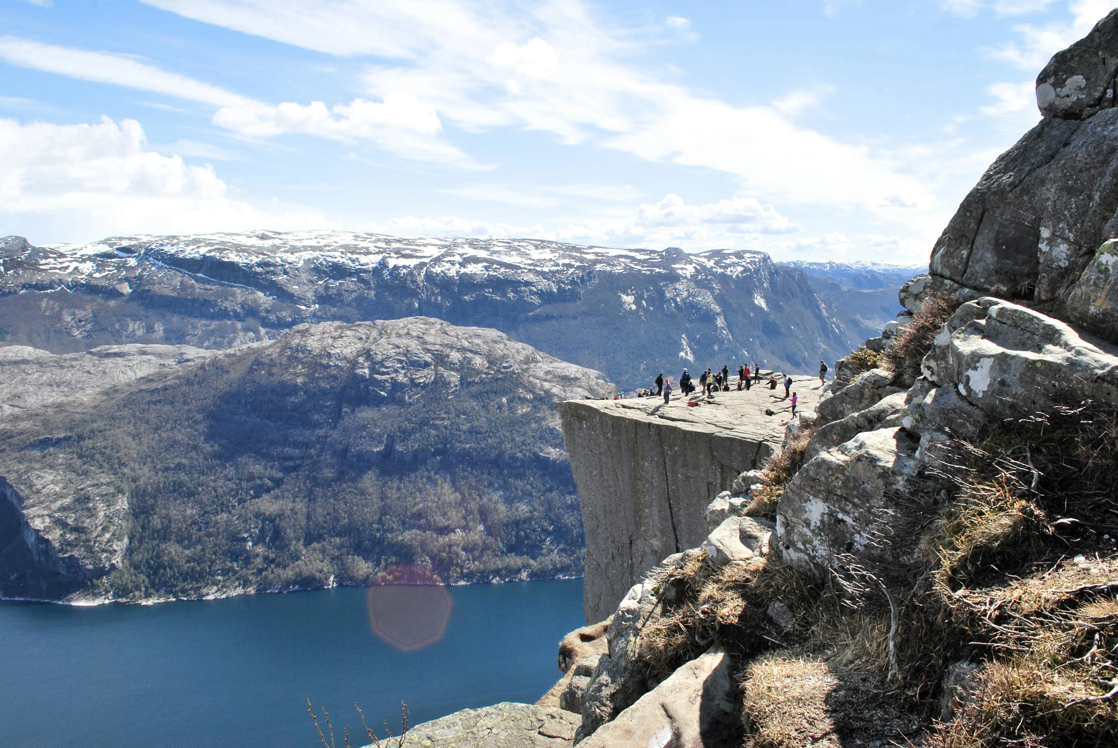 Preikestolen cliff edge overlooking Lysefjord at sunrise with hikers standing on flat rock surface