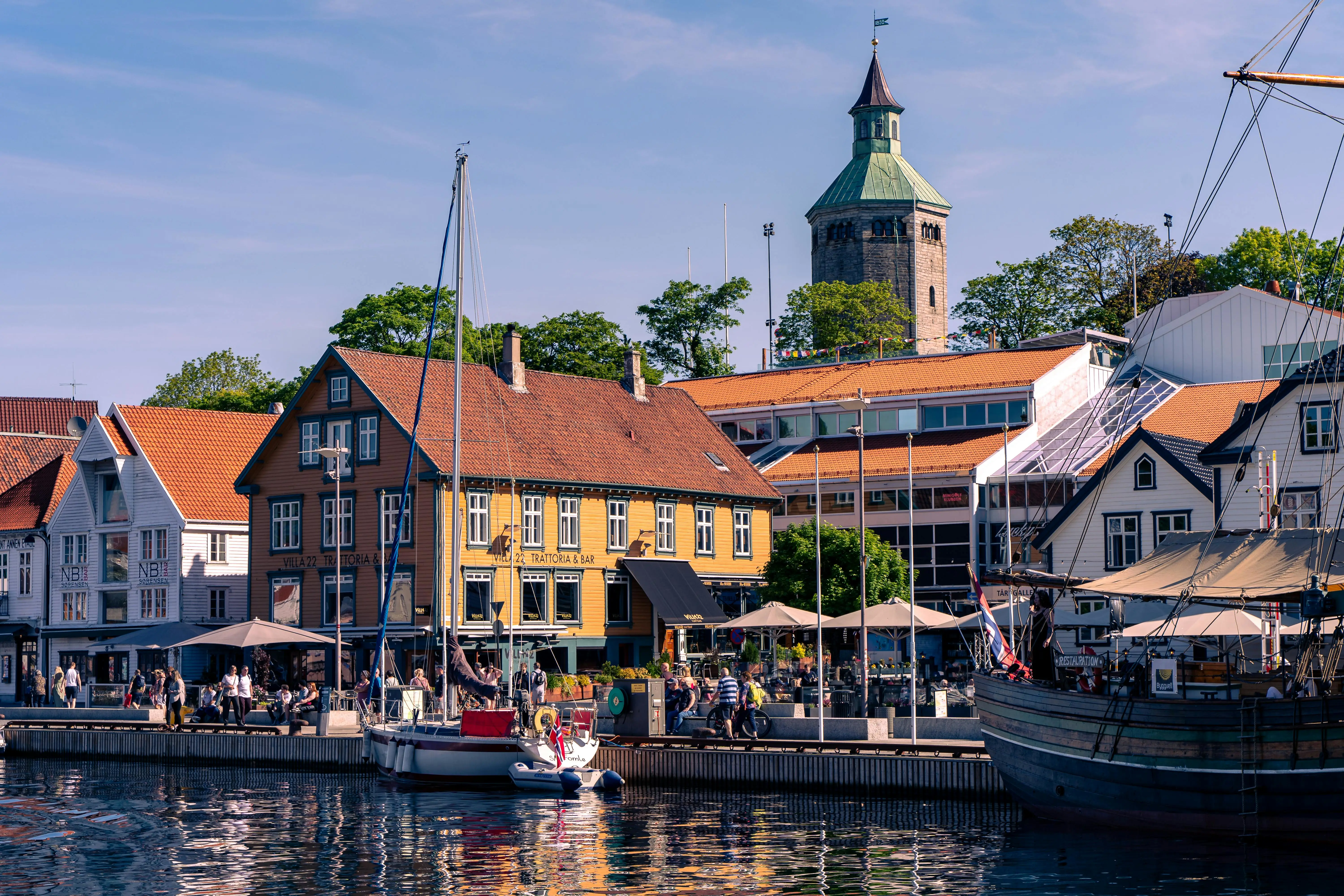 Stavanger Old Town white wooden houses along cobblestone street at golden hour with flower boxes and blue sky visible