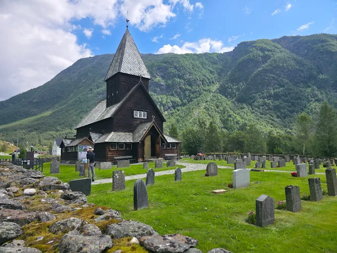 Røldal stave church Norway at sunset with dark wooden architecture and snowy mountain backdrop in Hardanger region