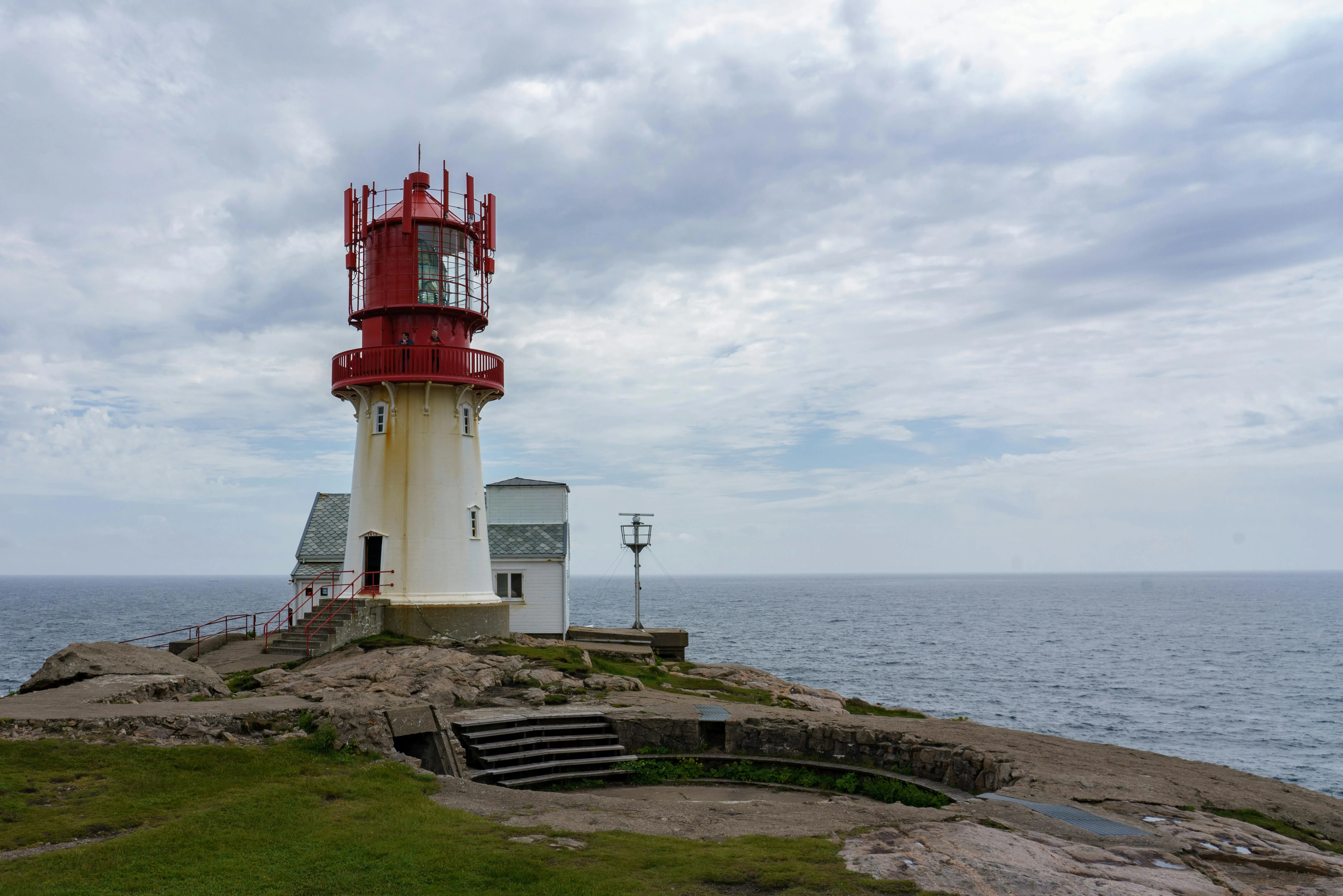 Lindesnes lighthouse Norway at sunset with white tower and rocky coastal cliffs overlooking North Sea waves