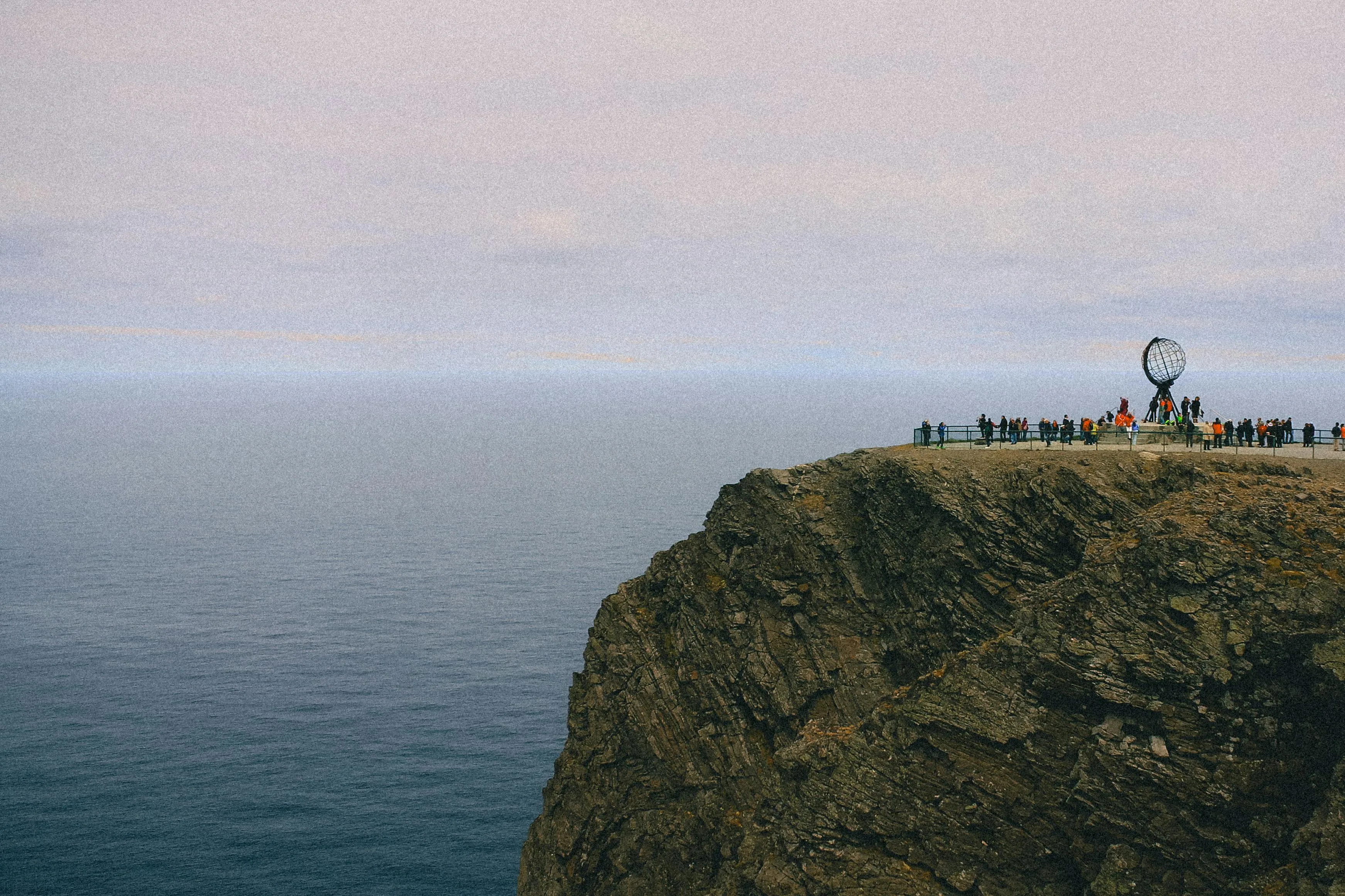 North Cape Norway cliff at midnight sun with golden globe monument and dramatic Arctic ocean horizon below