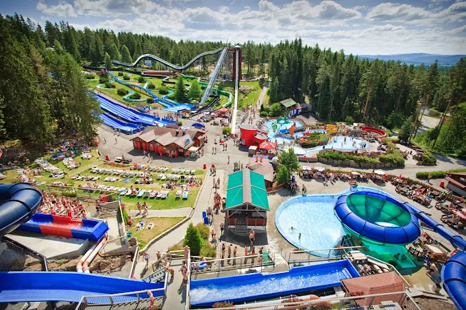 Bø Sommarland water park at golden hour with families sliding down colorful water slides against Norwegian forest backdrop, summer evening 2026