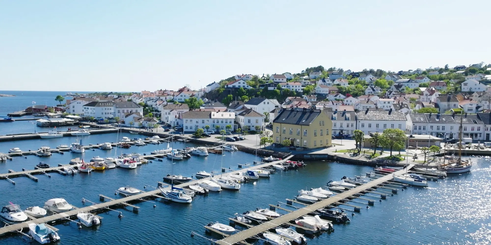 Risør white town Norway at sunset with historic wooden houses and calm harbor waters reflecting golden light