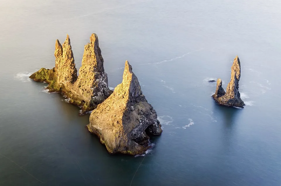 Reynisdrangar basalt sea stacks rising from Atlantic Ocean near Reynisfjara black sand beach under dramatic cloudy sky