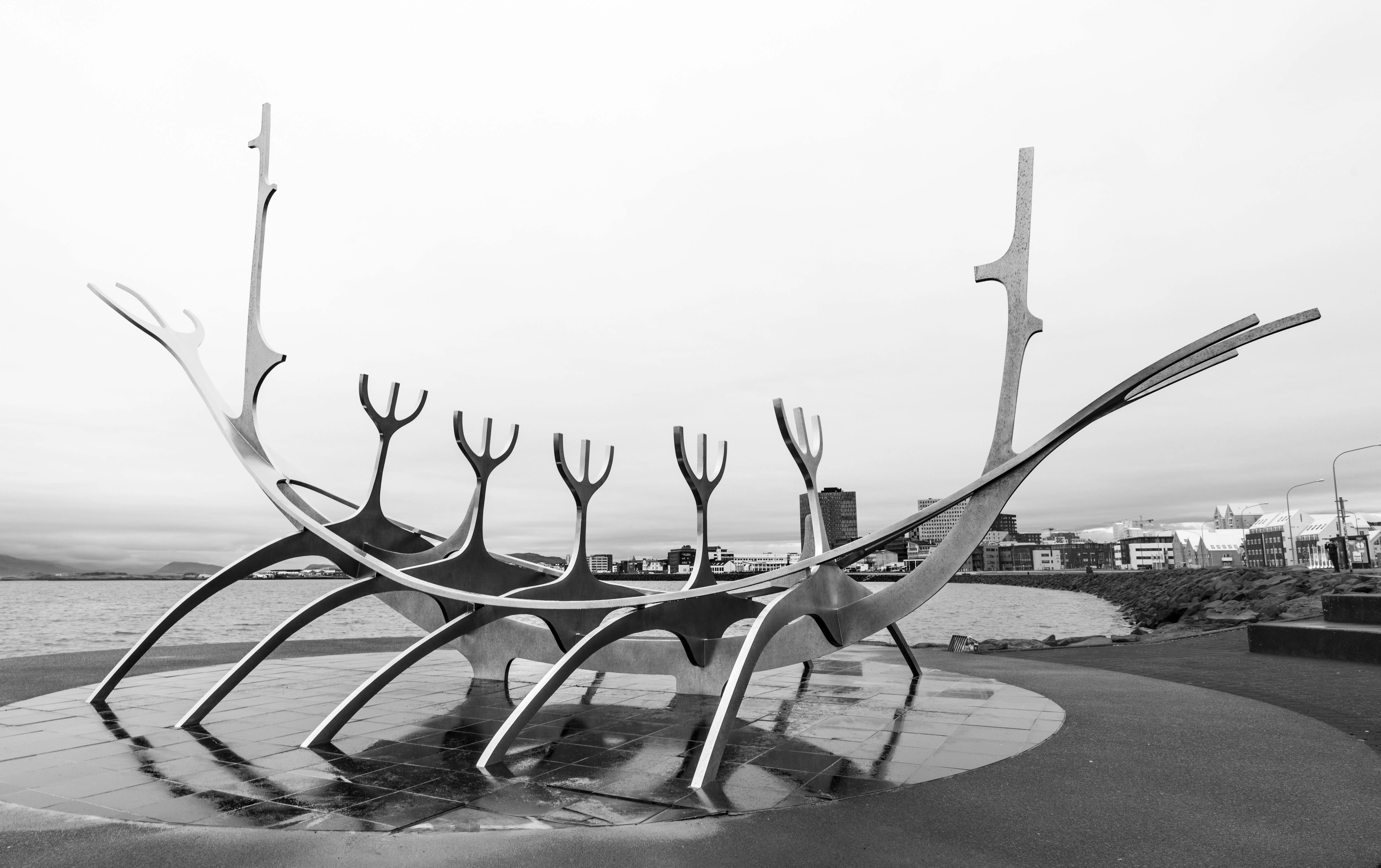 Sun Voyager sculpture gleaming against Reykjavík waterfront at sunset with Mount Esja backdrop and golden Arctic light