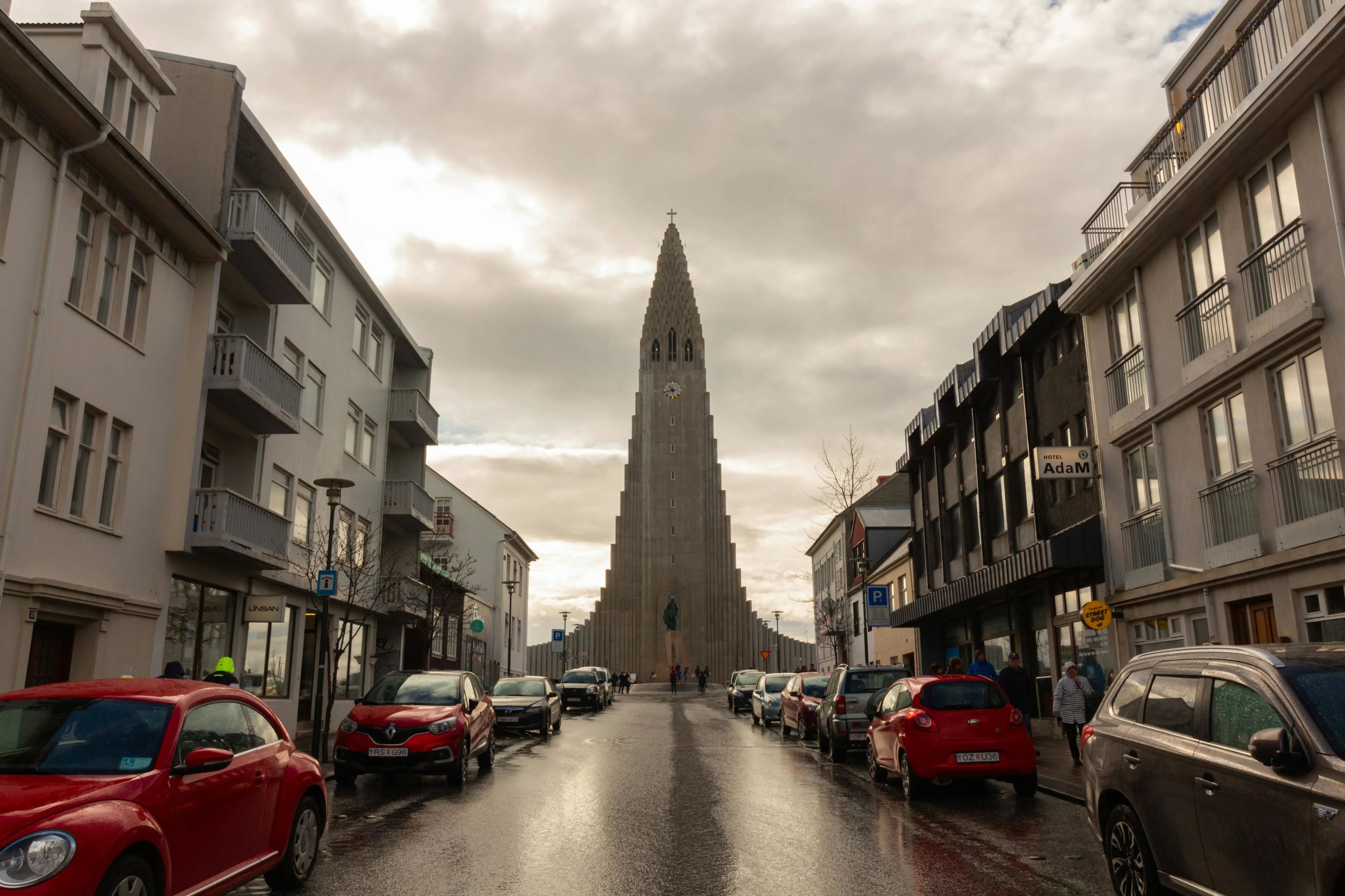 Hallgrímskirkja church tower overlooking Reykjavík cityscape at sunset with colorful rooftops and distant mountains under Nordic light