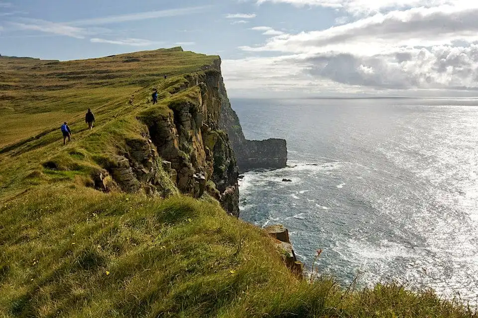 Dramatic Westfjords cliffs at sunset in Northwest Iceland, vertical basalt rock faces meeting Atlantic Ocean waves under golden light