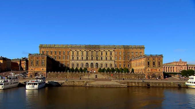 Stockholm City Hall tower reflecting in water at sunset with golden brick facade and blue sky